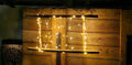 Warm white string fairy lights draped over a rustic wooden wall panel in a dimly lit interior setting.